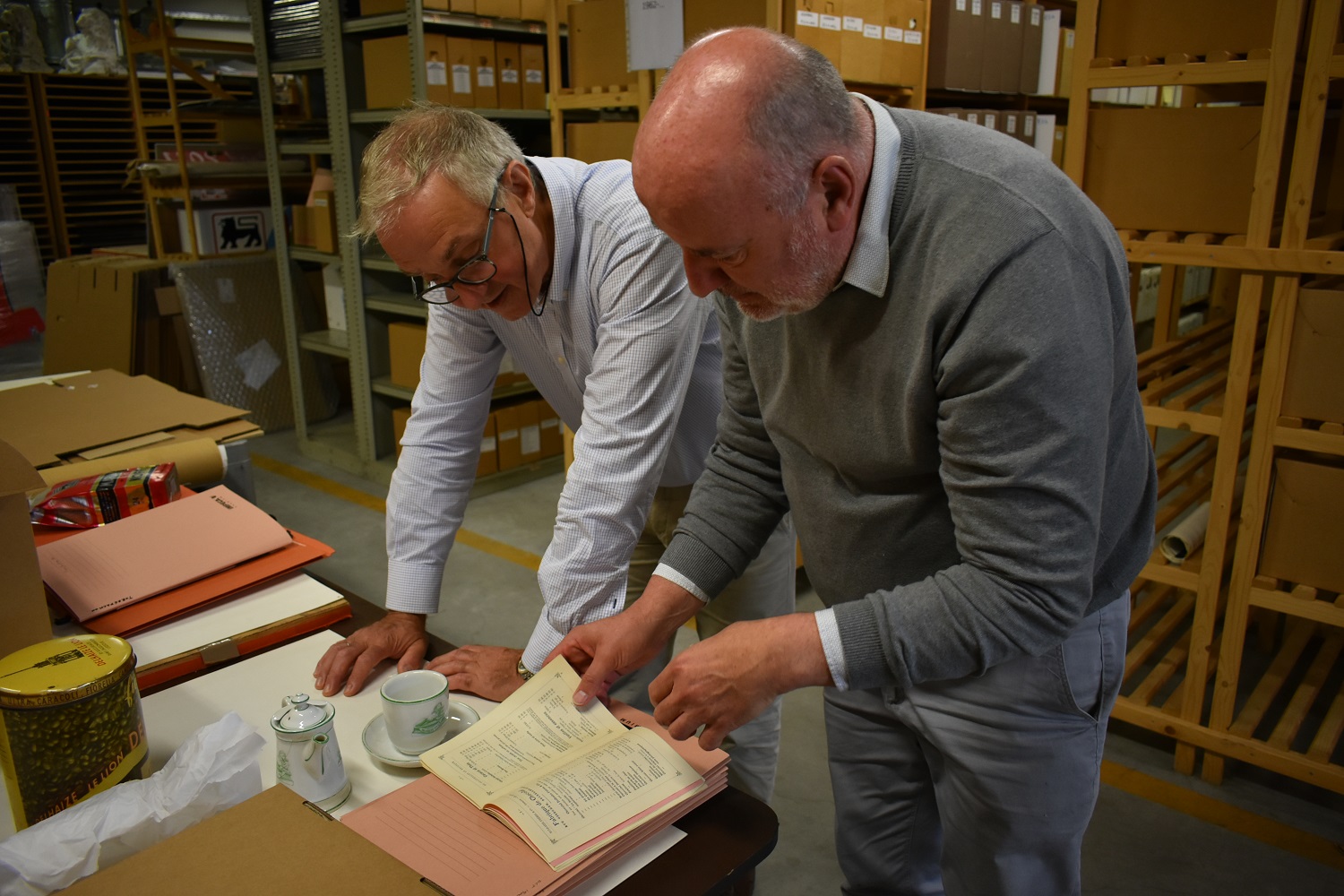 Guido bekijkt samen met de archivaris van Delhaize, Emmanuel Collet, uniek koffie-erfgoed uit deze periode.