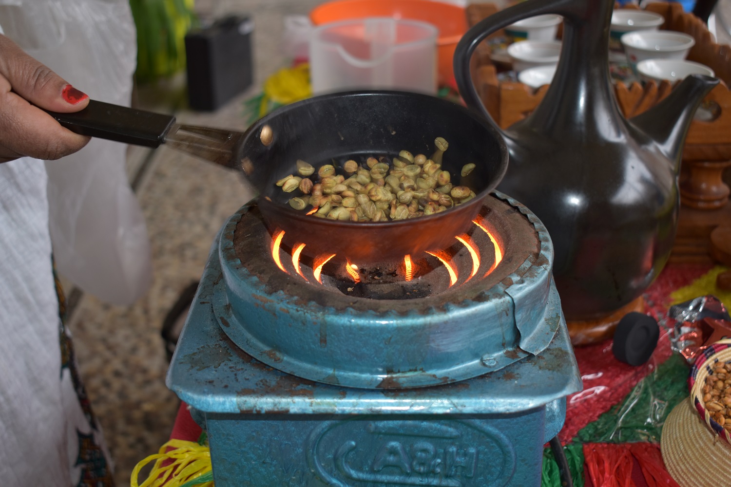 Groene koffiebonen worden gebrand in een pan op een houtskoolbrander. Collectie CAG.